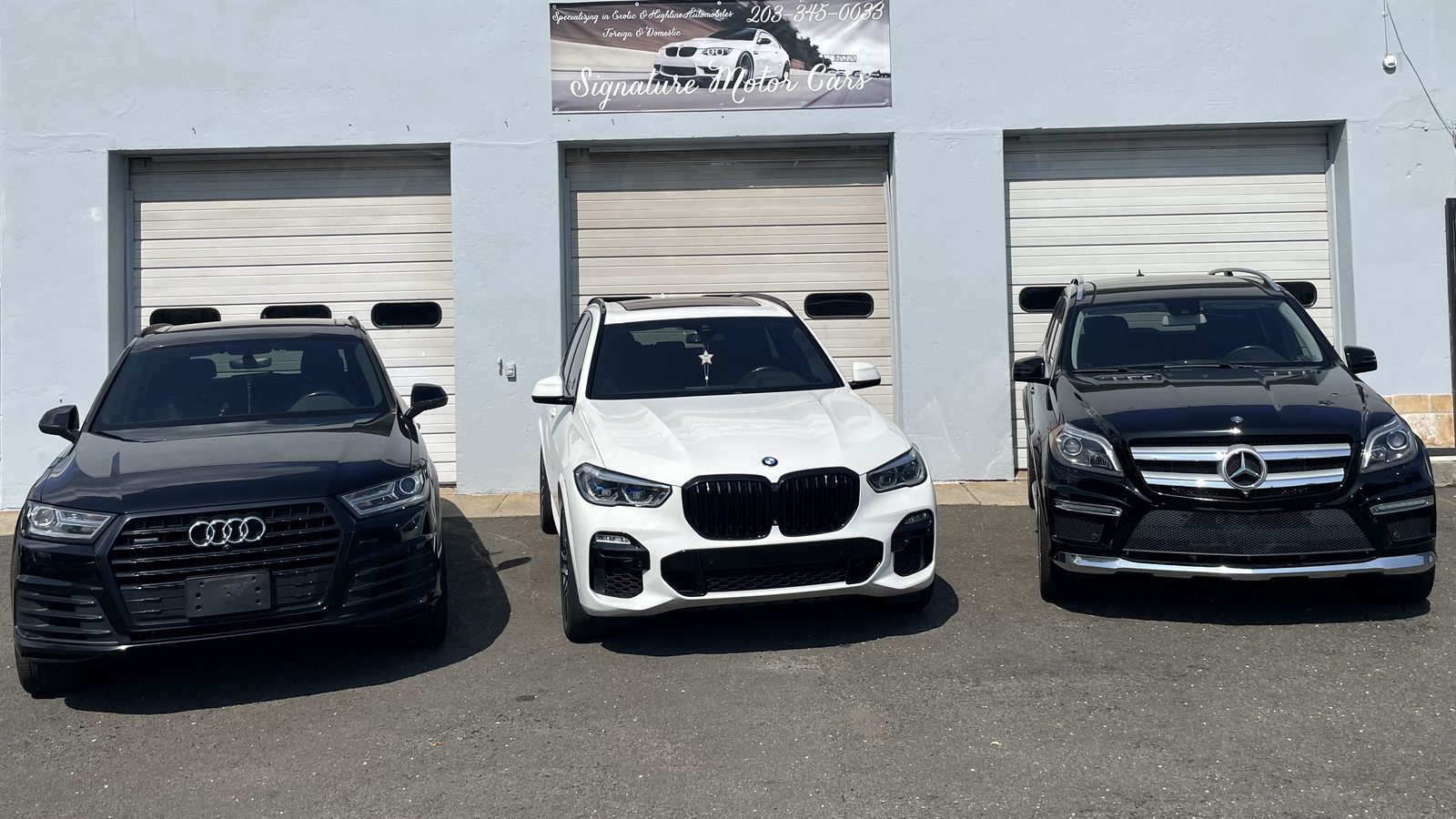 An Audi Q7, BMW X5 and Mercedes-Benz GL550 lined up outside the service bays